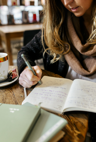 mujer escribiendo en cuaderno en cafeteria