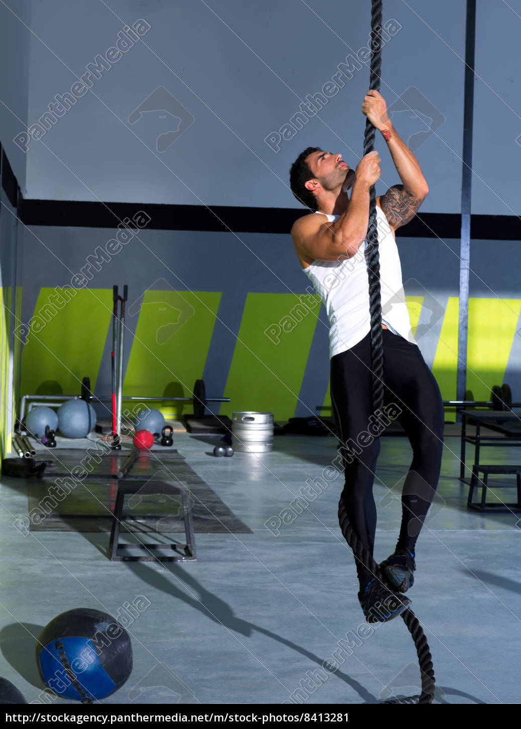 Hombre de gimnasio de crossfit con mano una cuerda de escalada